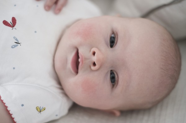 Cute baby girl (2-5 months) lying on bed.