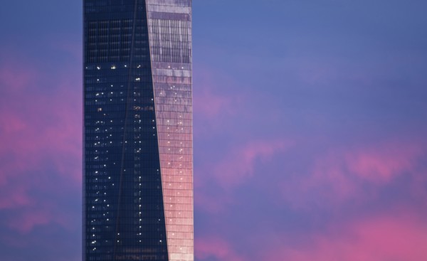 Part of One World Trade Center against dramatic sky at dusk. USA, New York, New York City.