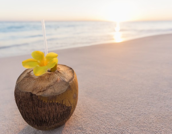 Tropical cocktail in coconut shell on sandy beach