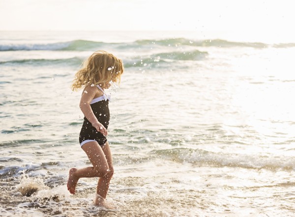 Girl (4-5) running in water on beach