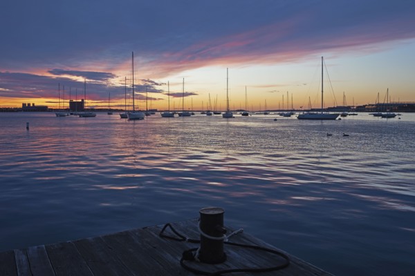 Boats moored in harbor at dawn