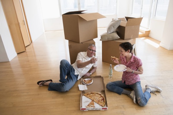 Couple eating pizza in new apartment.