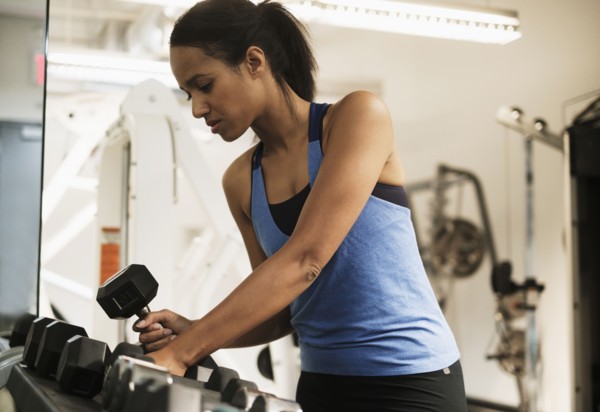 Woman choosing dumbbells for training.