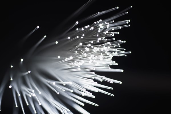 Bunch of glowing fiber optic cables on black background.