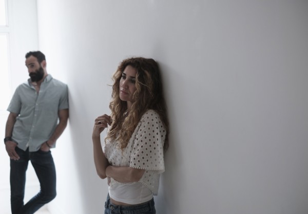 Estranged couple standing by wall.