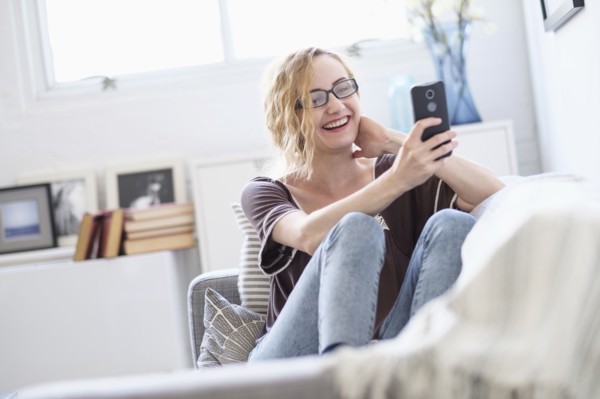 Woman sitting on sofa and using mobile phone.