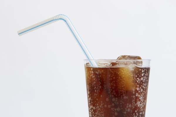 Studio shot of cold drink with ice cubes and plastic straw on white background