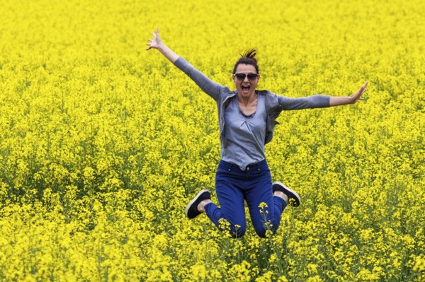 Italy, Tuscany, Woman jumping in canola field