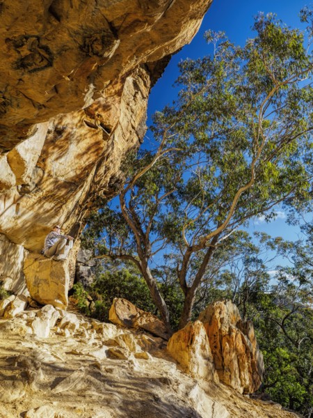 Australia, New South Wales, Blue Mountains, Mature woman resting on rock under cliff in mountain forest