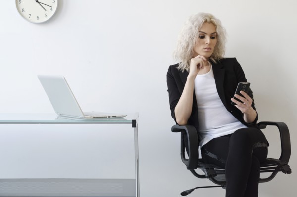 Young businesswoman using phone in office.