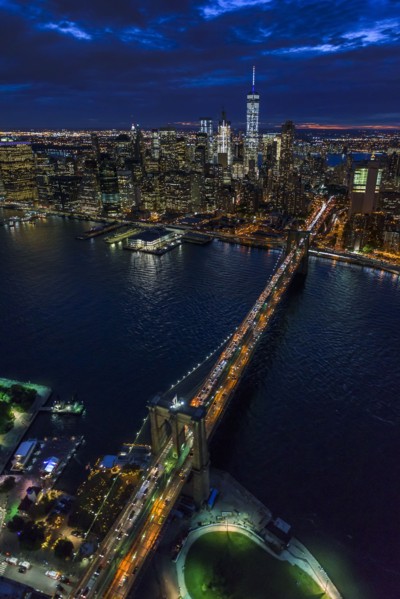 USA, New York, New York City, Manhattan, Aerial view of illuminated skyline with harbor and Brooklyn bridge at night.