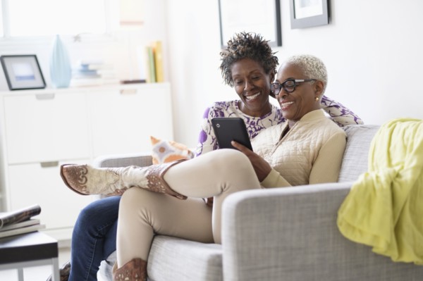 Smiling women using tablet in living room.