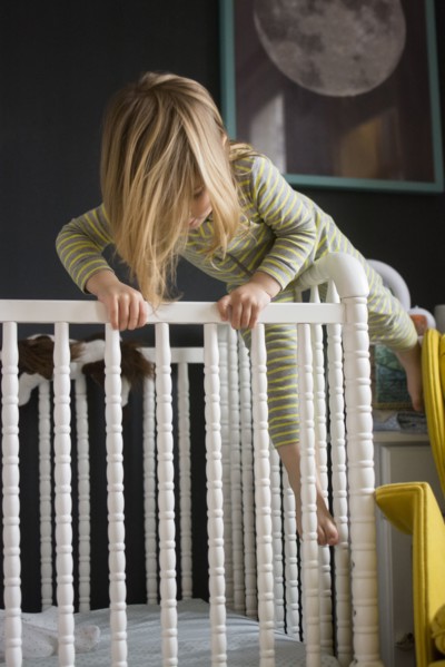 Girl (2-3) climbing on crib