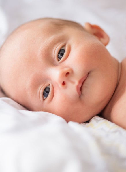 Baby boy (0-1 months) lying on bed