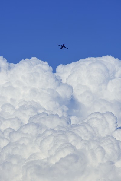 Airplane flying over large cloud