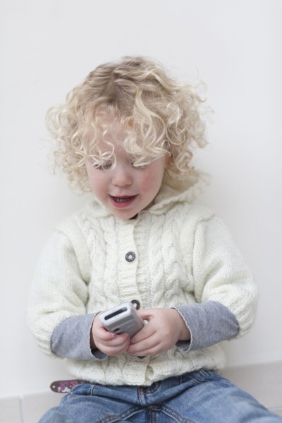 Portrait of blond girl (4-5) playing with mobile phone