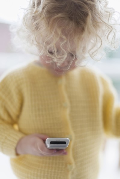 Blond girl (4-5) playing with mobile phone