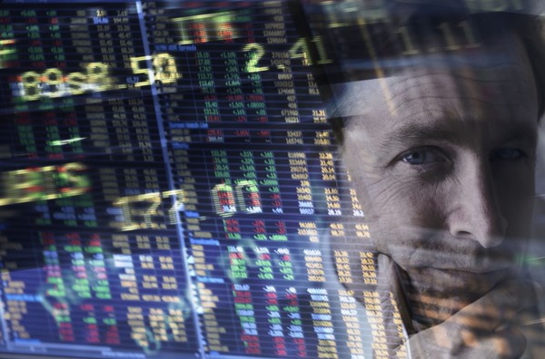 Face of mature man among stock exchange charts and numbers.