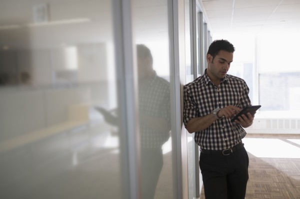 Young man standing in corridor with digital tablet.