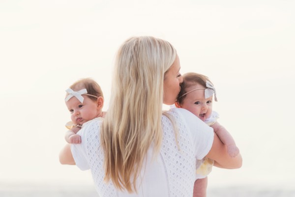 Happy mid adult mother kissing one of baby girls (2-5 months)