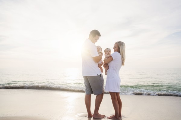 Happy family with two baby girls (2-5 months) at beach in sunlight