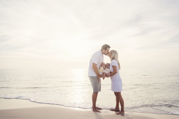 Couple with twins (2-5 months) kissing on seashore