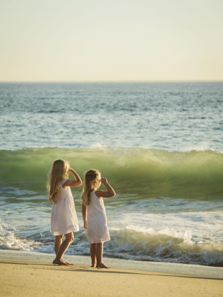 Girls (4-5, 6-7) standing on beach and looking at sea