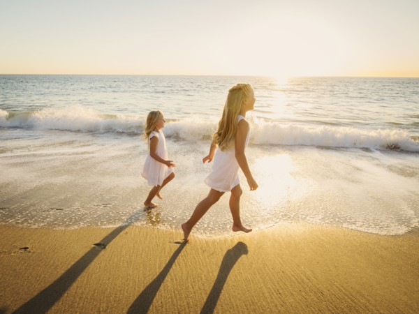 Girls (6-7, 8-9) running on beach