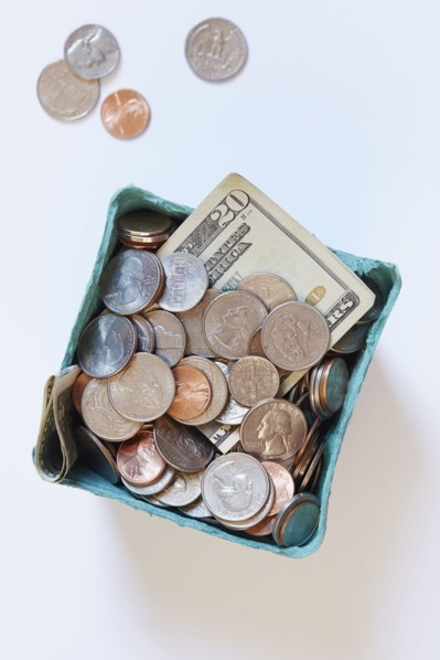 Coins and banknotes in carton box on white surface