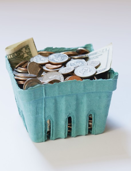 Coins and banknotes in carton box on on white surface