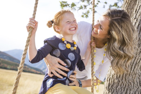 Mother with girl (4-5) sitting on swing