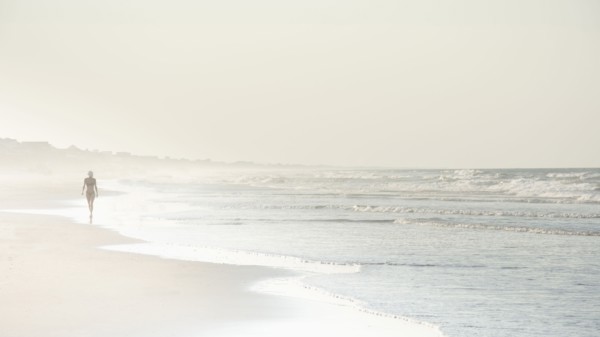 USA, North Carolina, Woman walking on empty beach