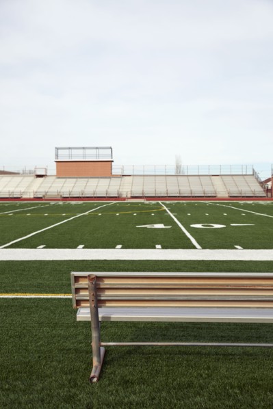 American football field with bench in foreground and empty bleachers in background