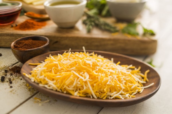Shredded cheese on wooden plate