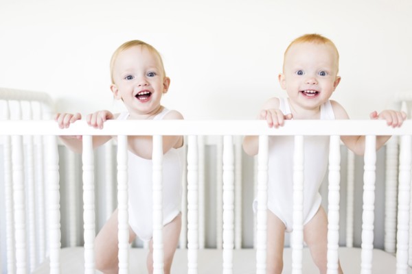 Twin brothers (12-17 months) standing in crib