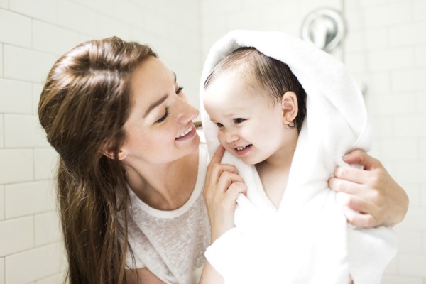 Mother wrapping son (4-5)  in towel in bathroom