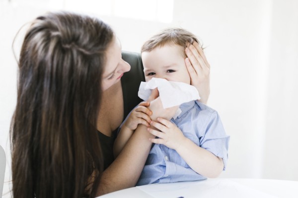 Young boy (4-5) blowing nose