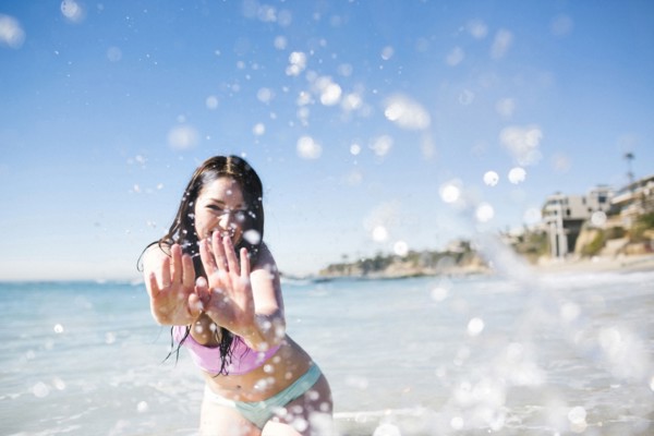 USA, California, Woman playing in water on Laguna Beach
