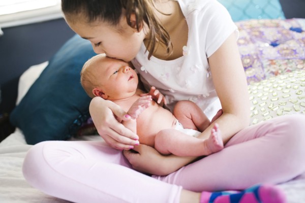 Girl (10-11) kissing brother with care (2-5 months)