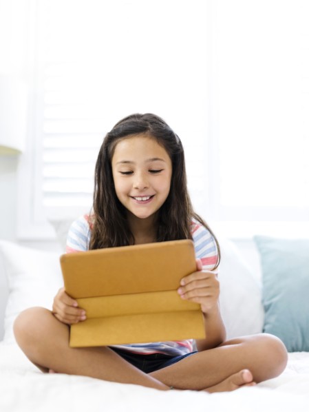 Smiling girl  (10-11) sitting and watching tablet