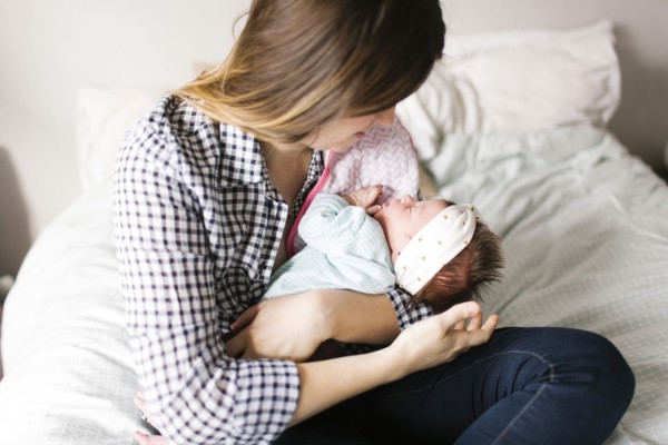 Young mother with baby girl (0-1 months) sitting in bedroom
