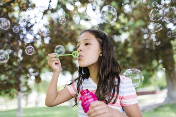 Portrait of girl ( 10-11 )  blowing soap bubbles