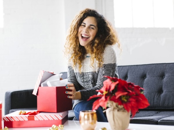 Happy woman on sofa opening Christmas gift