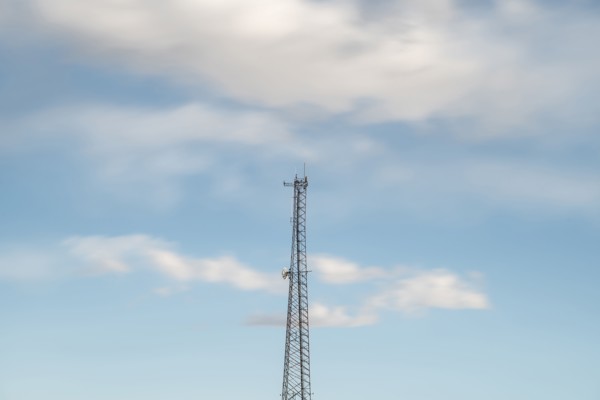 Top of communications tower with sky and clouds in background