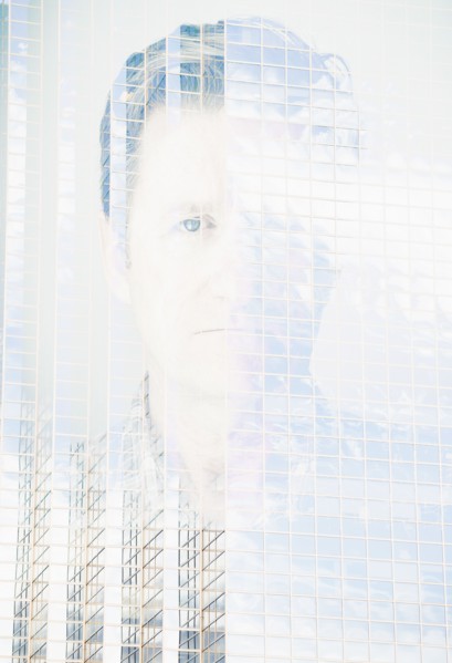 Double exposure portrait of mature man on office building facade