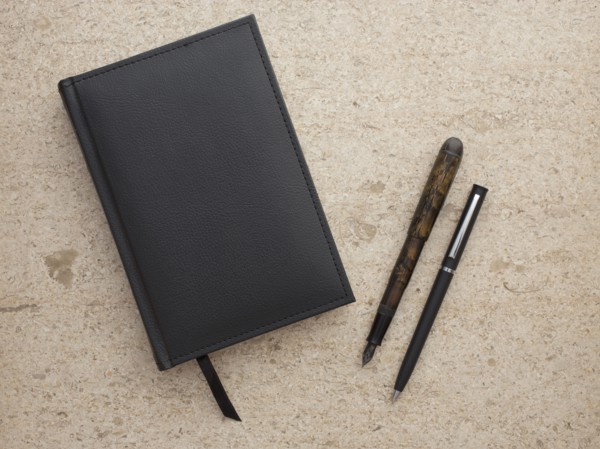 Studio shot of black notebook and two pens