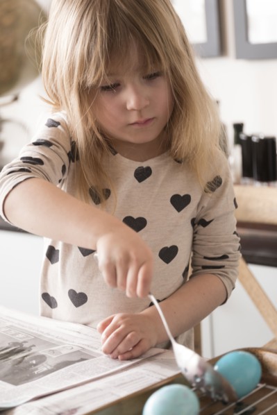 Girl (4-5) making colored Easter eggs