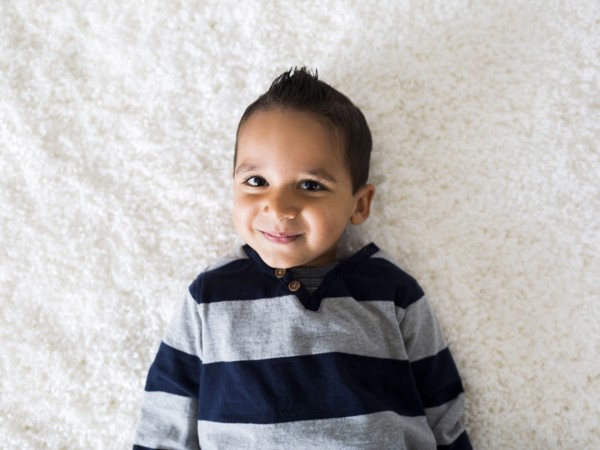 Boy (2-3) lying down on carpet