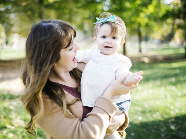 Portrait of mother carrying daughter (12-17 months) in park