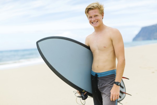 Man standing on beach and holding surfboard